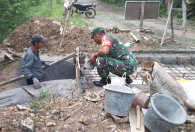 Babinsa Koramil Sapudi Sertu Agus Salim Saat Kerja Bakti Pembuatan Jalan Rabat Beton di Desa Kalowang Sapudi, Minggu (21/01/2024)