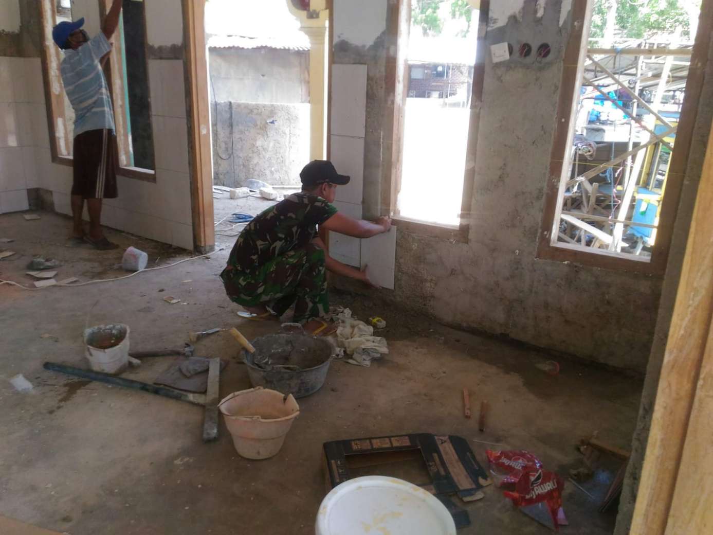 Bangun Sarana Ibadah, Babinsa Prenduan Bantu Warga Pasang Keramik Dinding Mushola