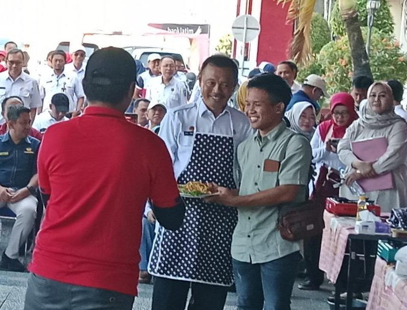 Sekda kabupaten Sumenep Edi Rasyadi Saat Memberikan Racikan Mie Goreng dalam Lomba Masak Peringatan HUT RI ke-80 Kepada Owner Media Locus Jatim Rifki A di Halaman Kantor Pemkab Sumenep, Rabu (06/08/2025)