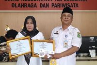Kadisbudparpor Sumenep Moh. Iksan SPd MT Saat Menyerahkan Penghargaan Kepada Kepala SDN Pajagalan I Sumenep Hariyani SPd MPD 