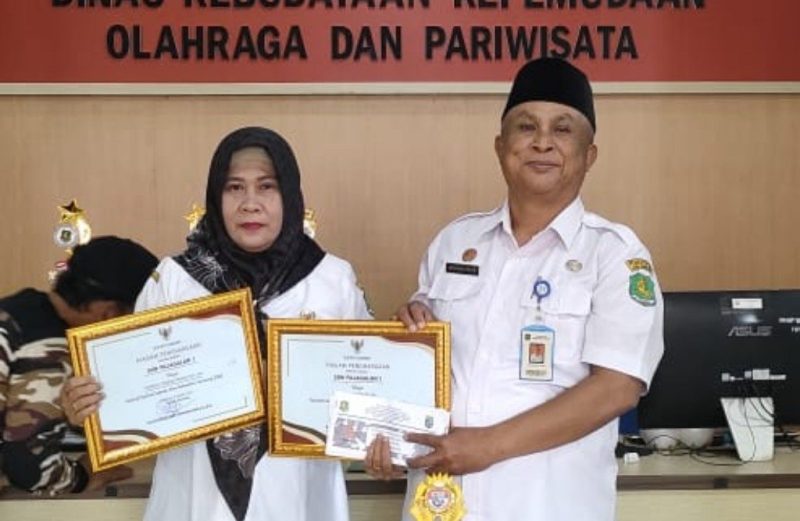 Kadisbudparpor Sumenep Moh. Iksan SPd MT Saat Menyerahkan Penghargaan Kepada Kepala SDN Pajagalan I Sumenep Hariyani SPd MPD 