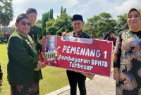 Wakil Bupati Sumenep menyerahkan penghargaan kepada Notaris Dr. Naghfir, S.H., M.Kn., sebagai penerima Anugerah Pajak Daerah 2025 kategori Pembayaran Bea Perolehan Hak atas Tanah dan Bangunan (BPHTB) Terbesar, Jum'at (31/10/2025)