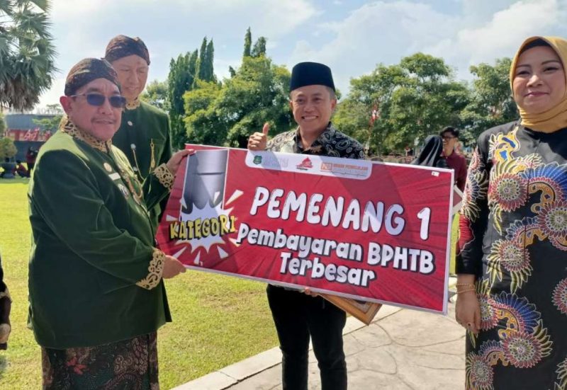Wakil Bupati Sumenep menyerahkan penghargaan kepada Notaris Dr. Naghfir, S.H., M.Kn., sebagai penerima Anugerah Pajak Daerah 2025 kategori Pembayaran Bea Perolehan Hak atas Tanah dan Bangunan (BPHTB) Terbesar, Jum'at (31/10/2025)