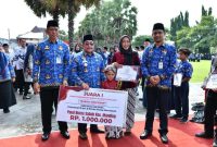 Wakil Bupati Sumenep KH. Imam Hasyim Didampingi Plt. Sekdakab Drs. Syahwan Efendi dan Kepala Disdik Agus Dwi Saputra Saat Memberikan Penghargaan Kepada Guru Dan Anak Didik Yang Berprestasi