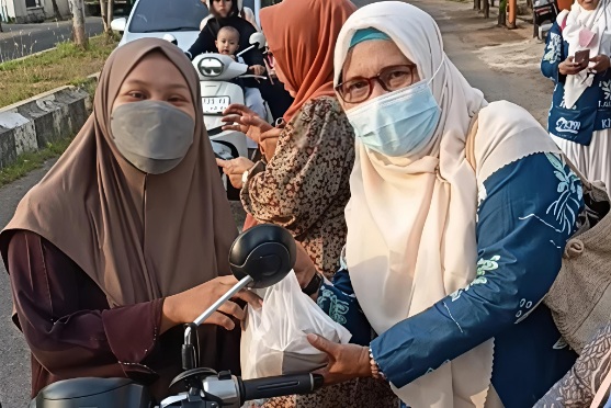 Ketua DPD KPPI Sumenep Yusnaniyah MPd Saat Memberikan Bungkusan kepada Warga 